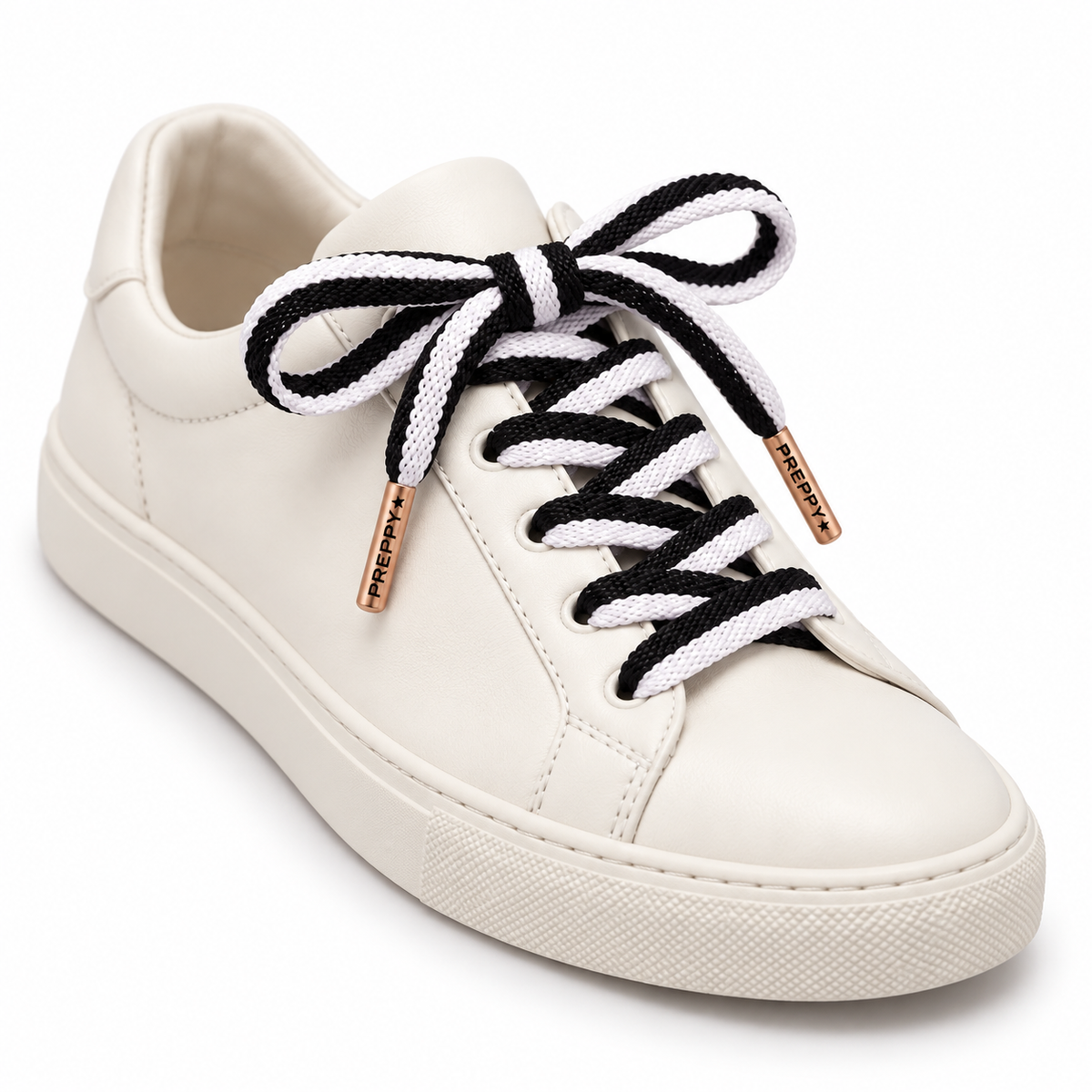 white sneaker with black and white shoelaces and rose gold aglets that say preppy 