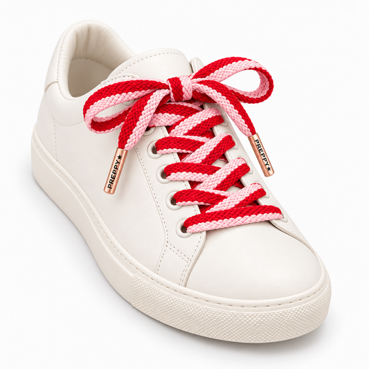 A white leather low-top sneaker with red and pink braided laces tied in a bow, featuring rose gold metal eyelets with the brand name 'FREDDY'S' on them, set against a plain white background.